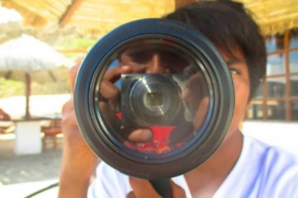Un chico detrás de un gran lente de cámara de video