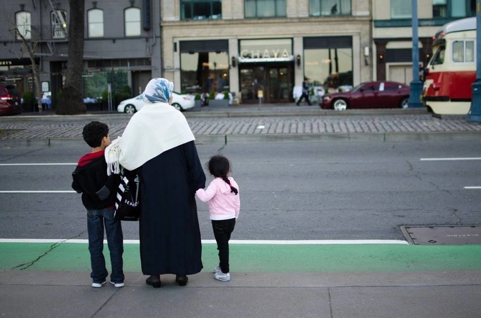 Mujer migrante con dos niños de la mano