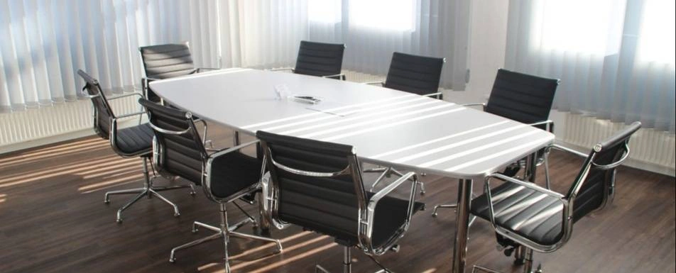 A conference room with a long table and empty chairs.