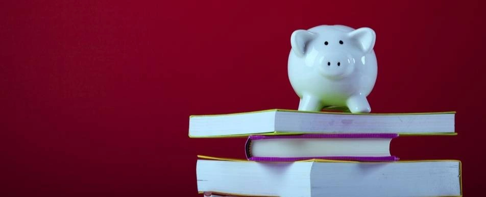 A piggy bank on top of a pile of books.