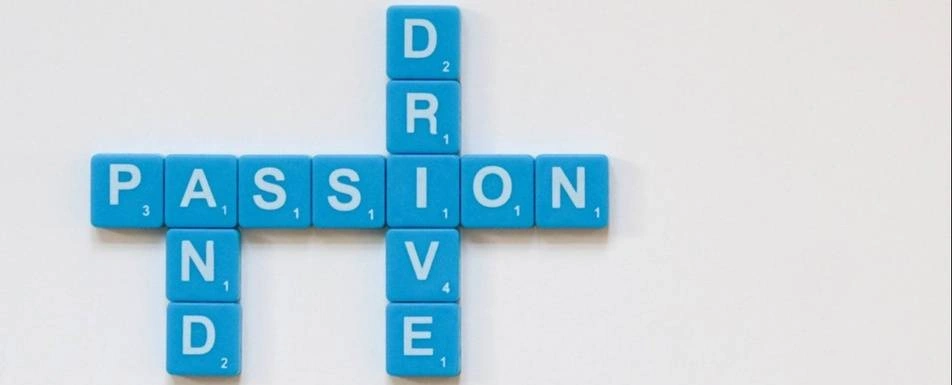 Scrabble tiles spelling out 'Passion and Drive'.