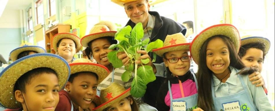 Stephen Ritz poses with a group of children, all wearing cowboy hats.