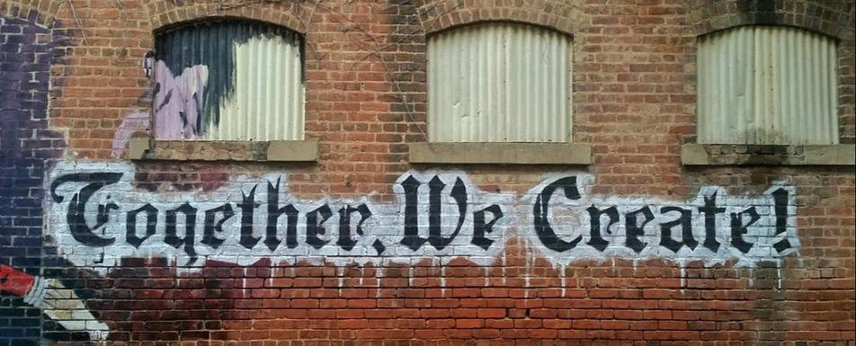 A graffiti art on a wall that says 'Together We Create!'.