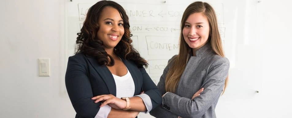two women with crossed arms smiling