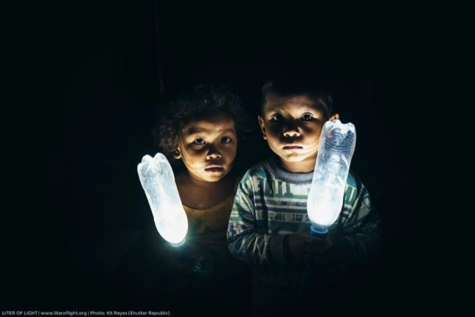 Un niño y una niña con botellas con luz en medio de la noche