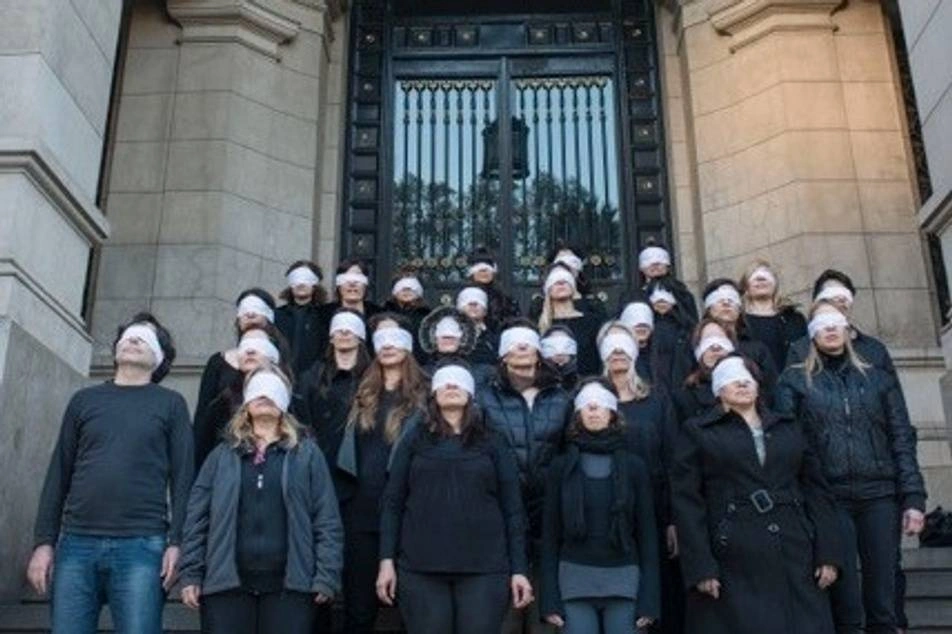 Varias personas frente a una institución de justicia, con los ojos vendados