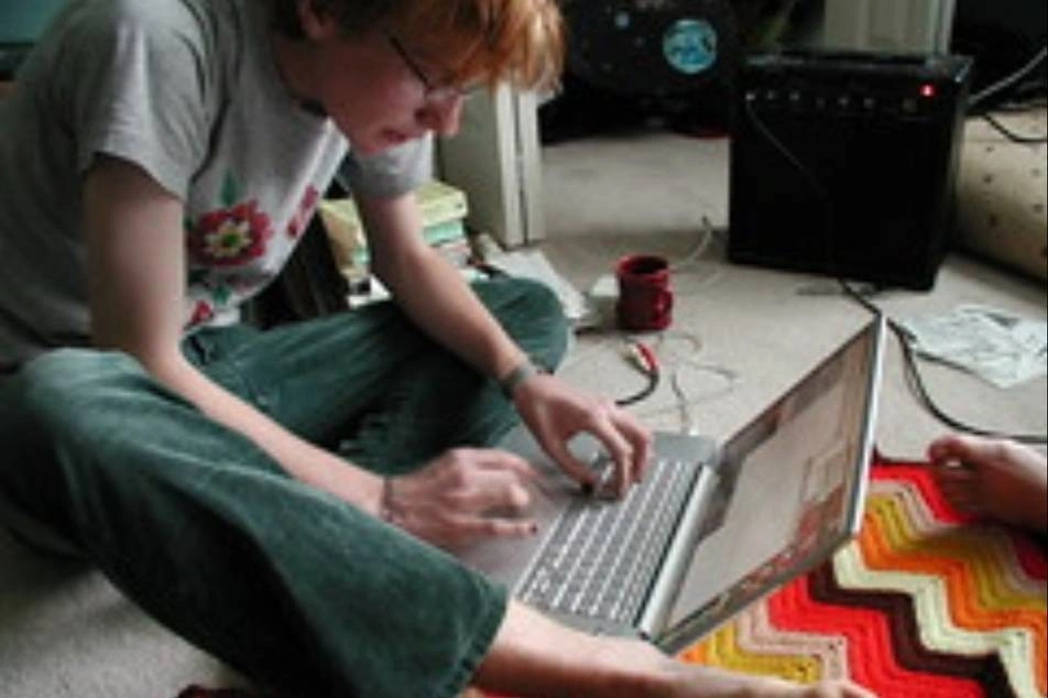Un chico trabajando en una laptop, sentado en el piso