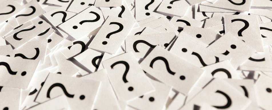 A pile of a papers with question marks on it.