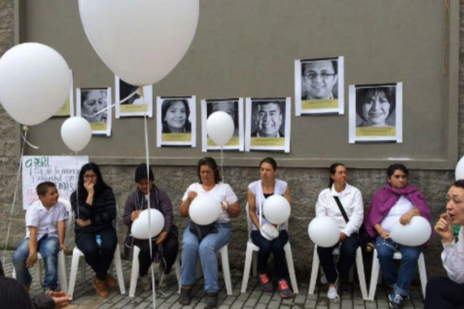 A group of people hold white balloons in their laps.