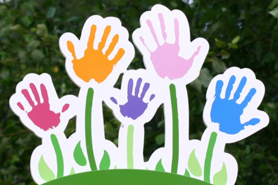 Manualidad de unas plantitas de cartón de colores en el que en lugar de flores hay manos levantadas