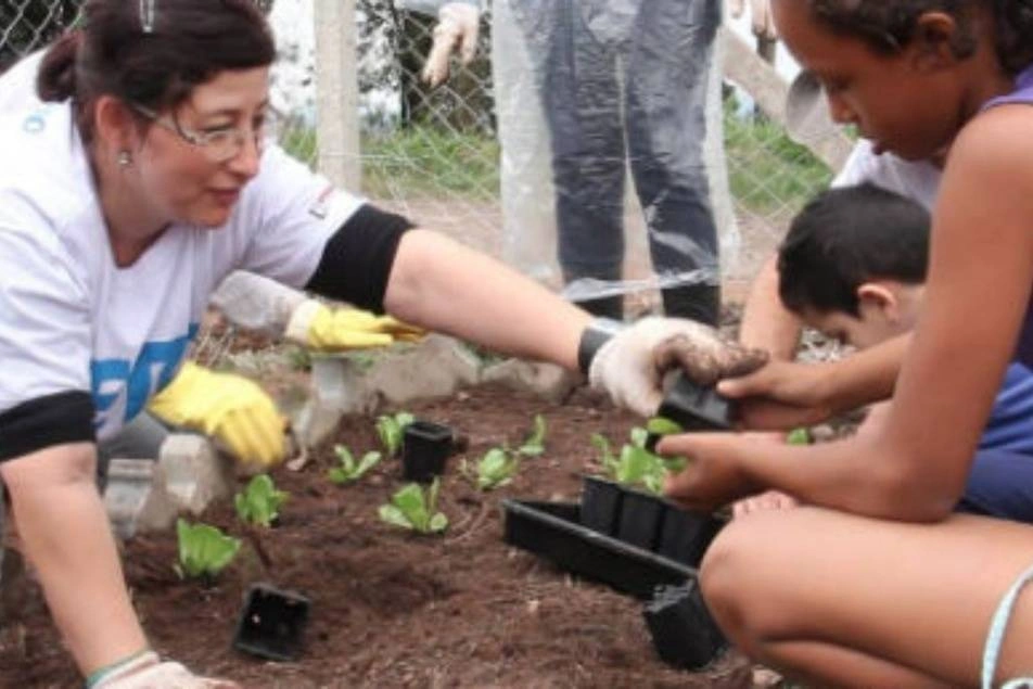 Voluntaria enseñando a una mujer a sembrar en la huerta