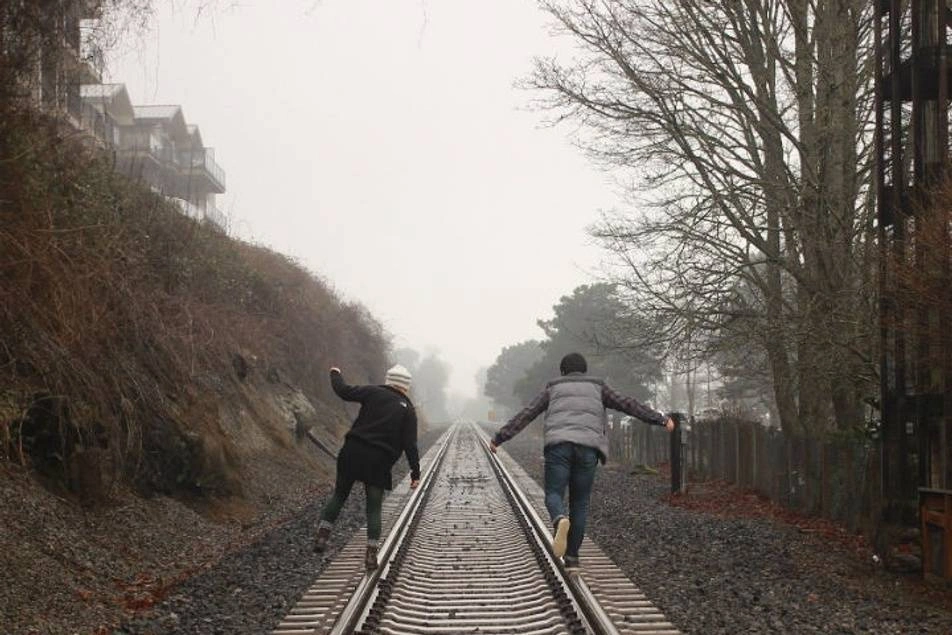 Dos personas caminando por los rieles de una vía de tren
