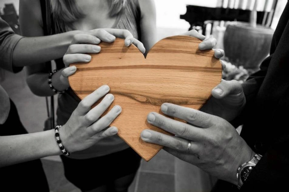 personas sosteniendo un corazón de madera