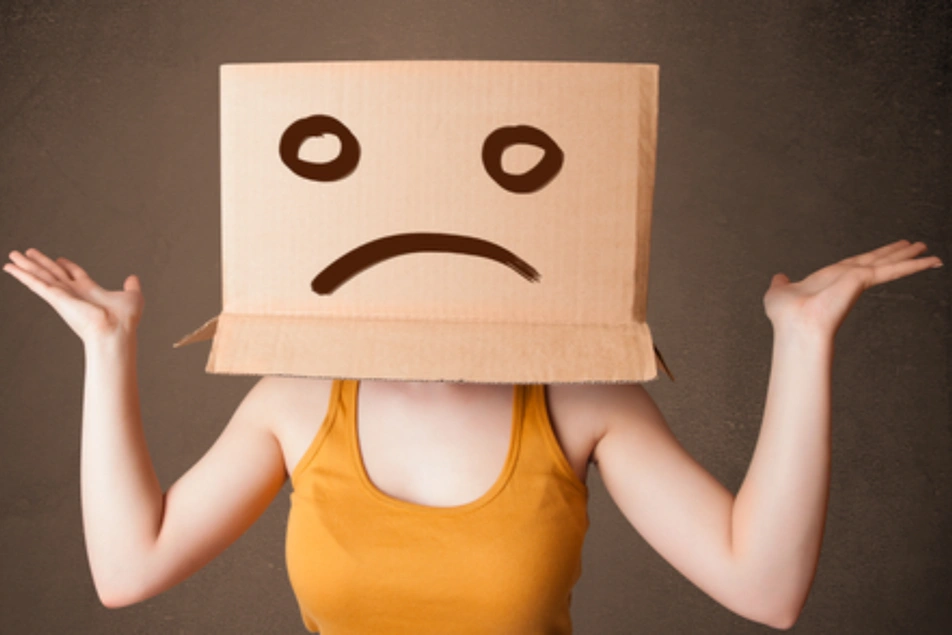 Mujer con una caja de cartón con una cara triste en la cabeza