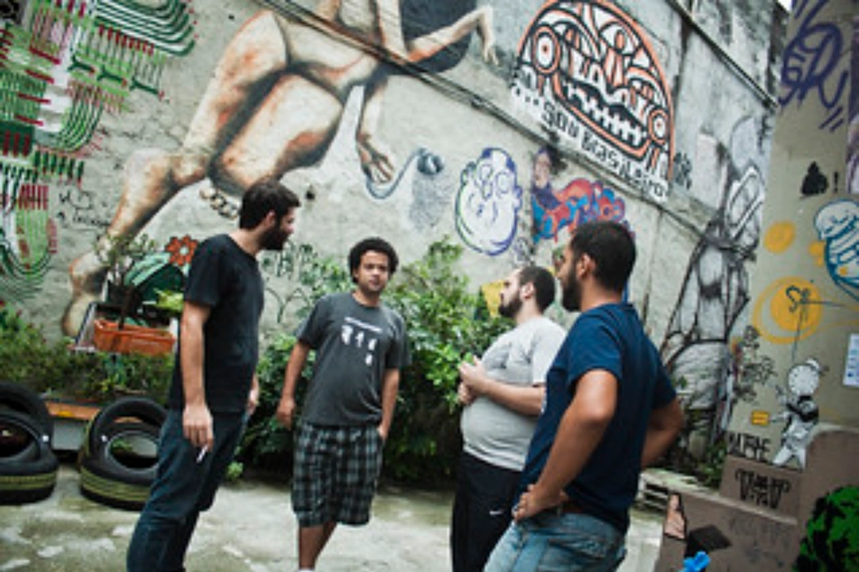 Un grupo de 4 chicos conversando en un patio con murales