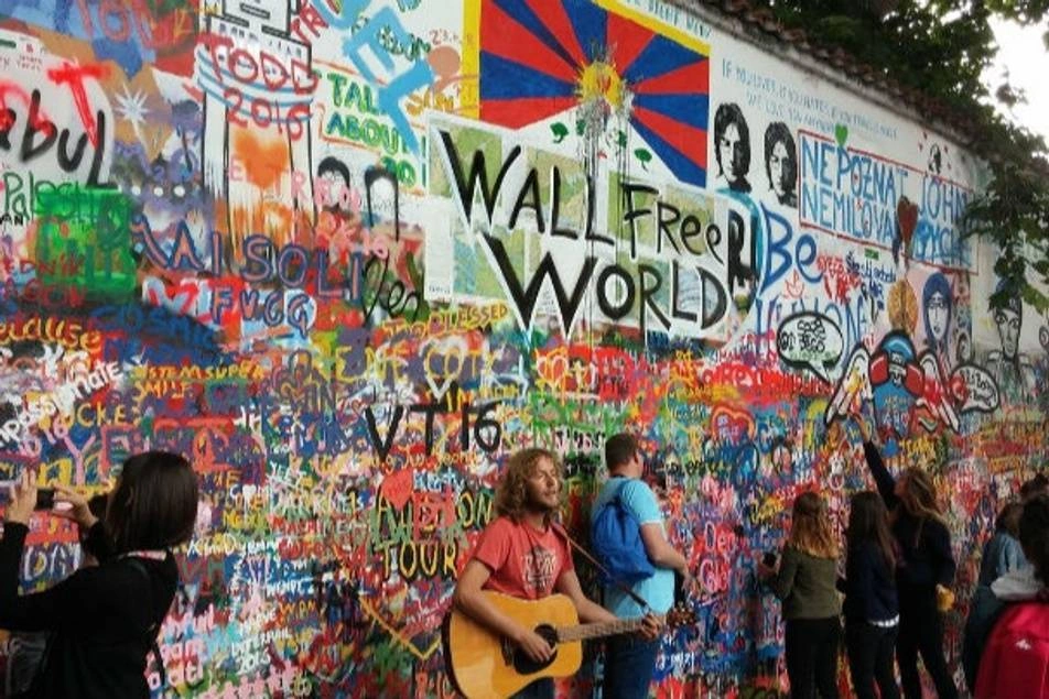 Cantante tocando guitarra frente a pared llena de graffitis