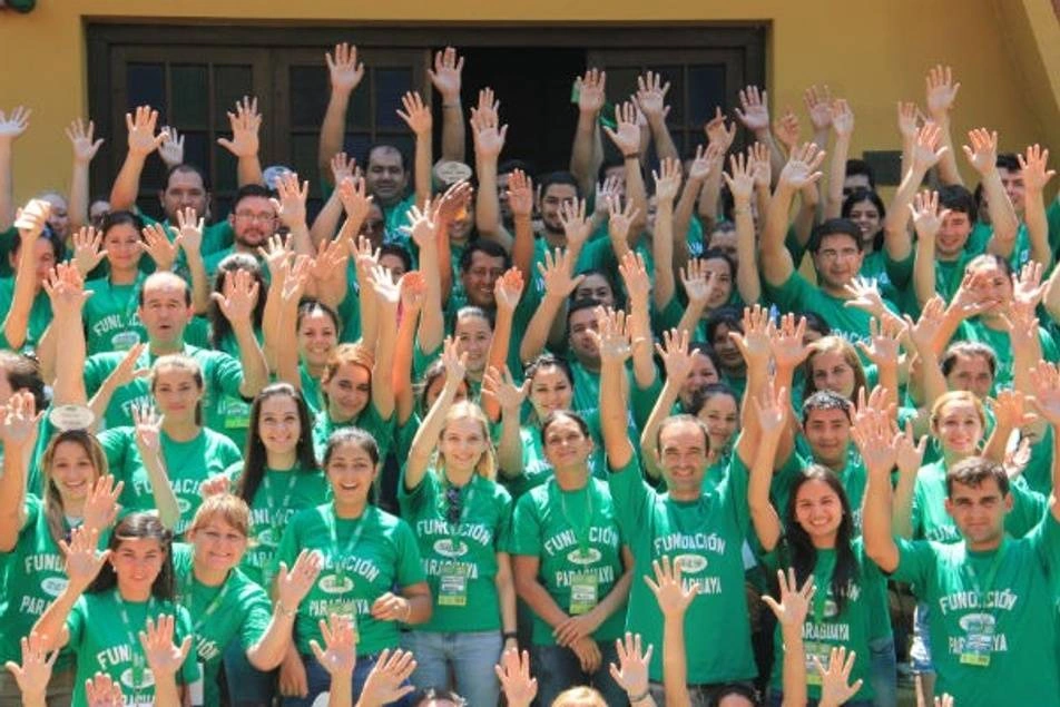 Un grupo grande voluntarios levantando sus manos