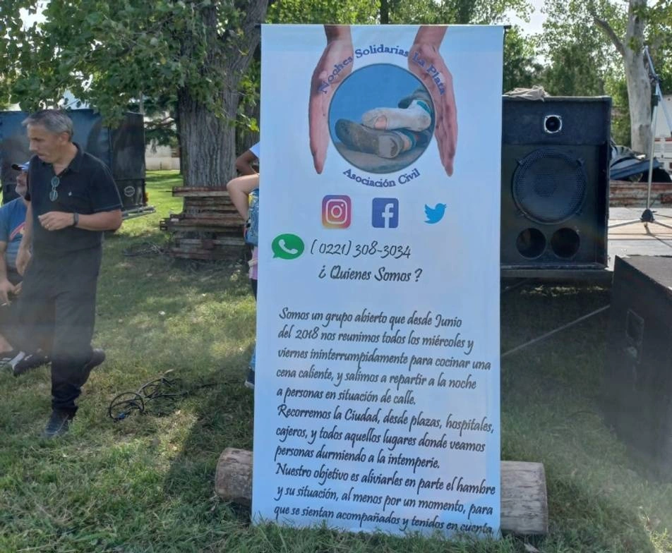 Voluntario junto a un banner de Noches Solidarias Platenses