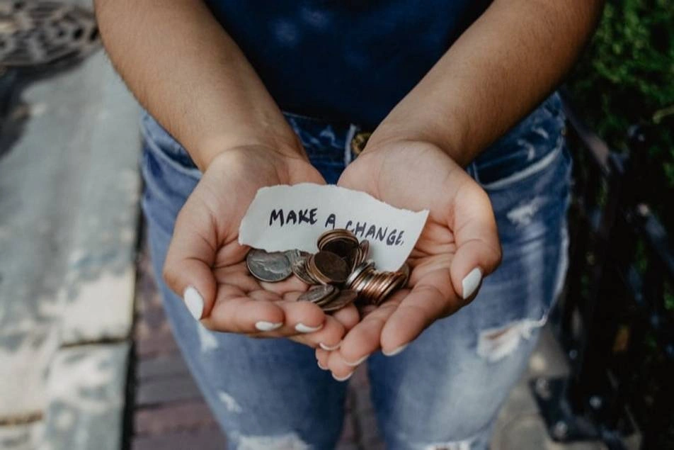Una persona sosteniendo en sus manos dinero con un letrero que dice "haz la diferencia"