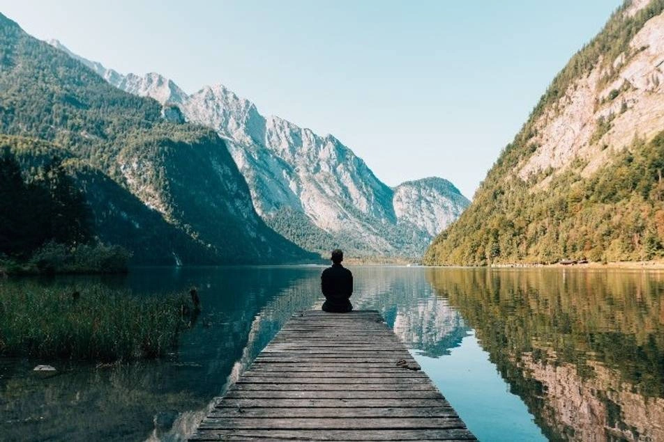 Hombre meditando frente a un lago