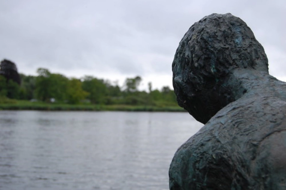 Una escultura de piedra de un hombre mirando un río