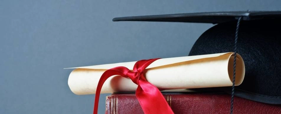 A book, a diploma and a graduation cap.